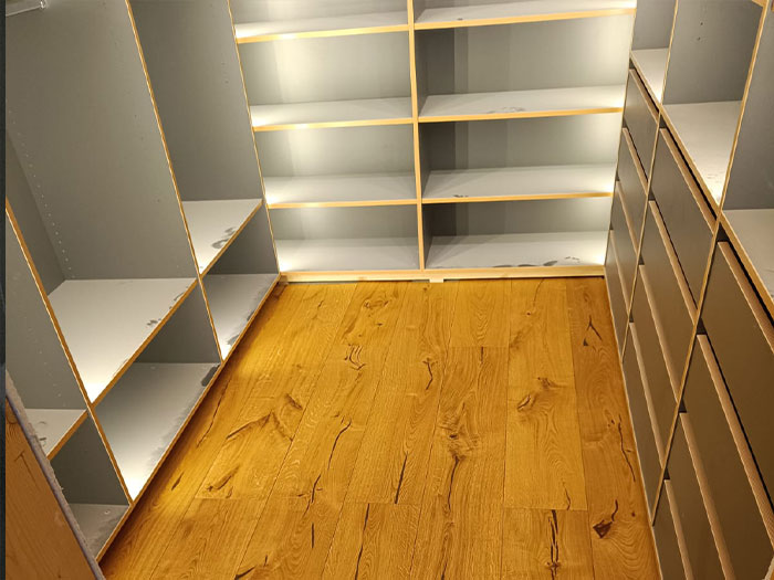 Leerer Raum mit Regalen und Holzfußboden.