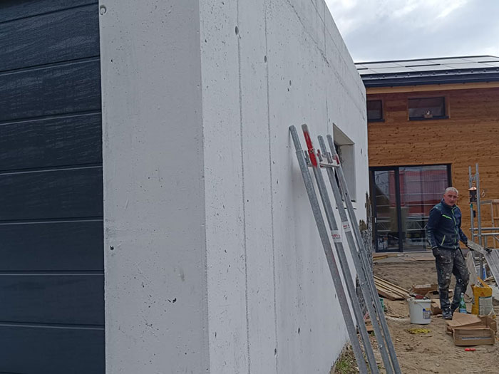 Bauarbeiter am Haus mit blauer Wand und Gerüst.
