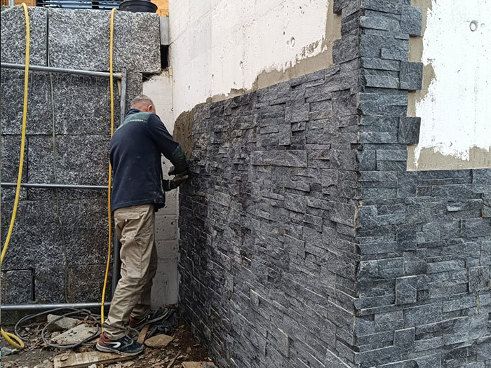 Handwerker verlegt Steine an einer Wand.