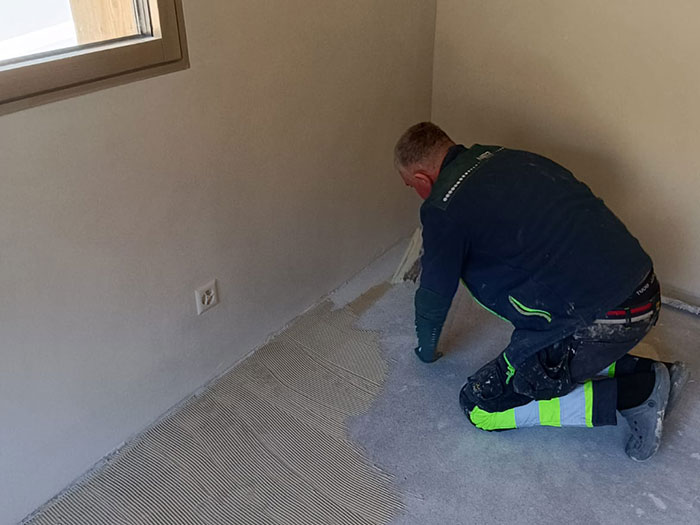 Handwerker verlegt neuen Bodenbelag in Raum.