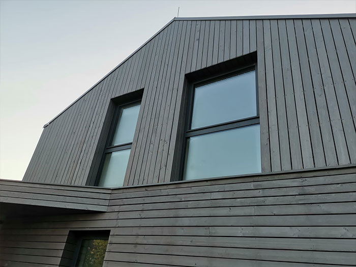 Moderne Holzfassade mit großen Fenstern