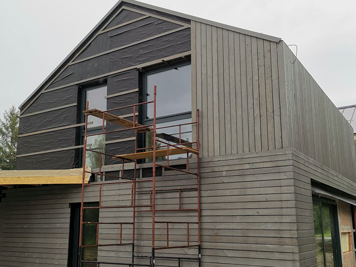 Modernes Haus mit Gerüst und großen Fenstern.